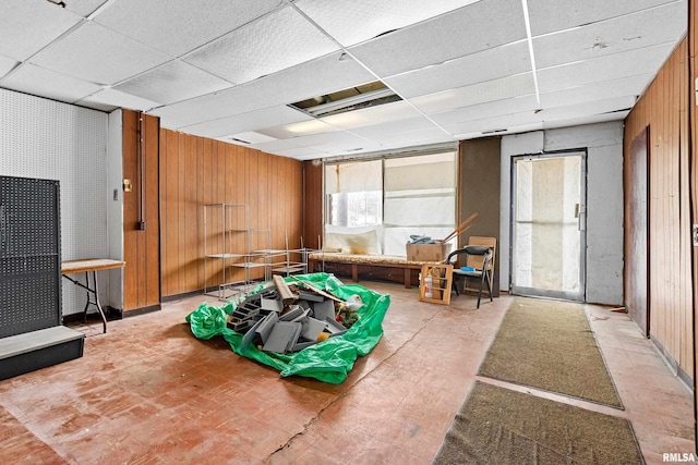 recreation room with wood walls and a drop ceiling