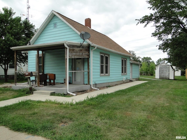 rear view of property featuring a storage unit, a porch, and a yard