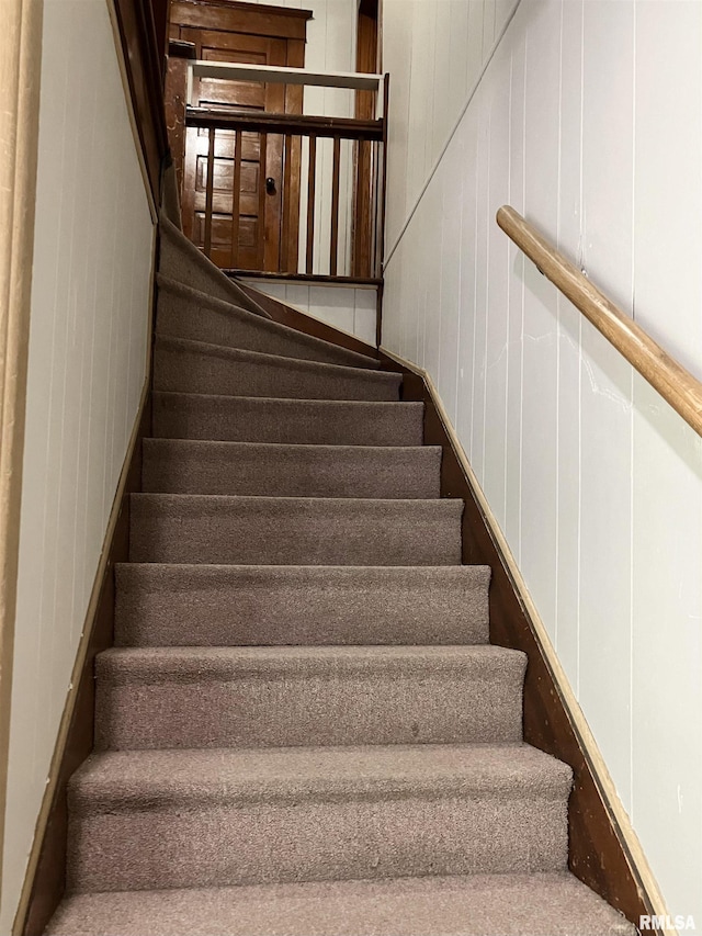 stairway featuring wood walls