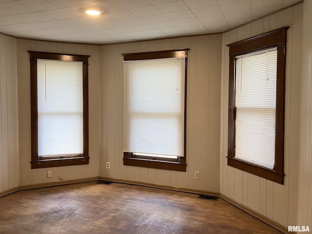 unfurnished room with wood-type flooring and wood walls