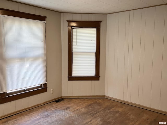 spare room featuring hardwood / wood-style flooring, wooden walls, and ornamental molding