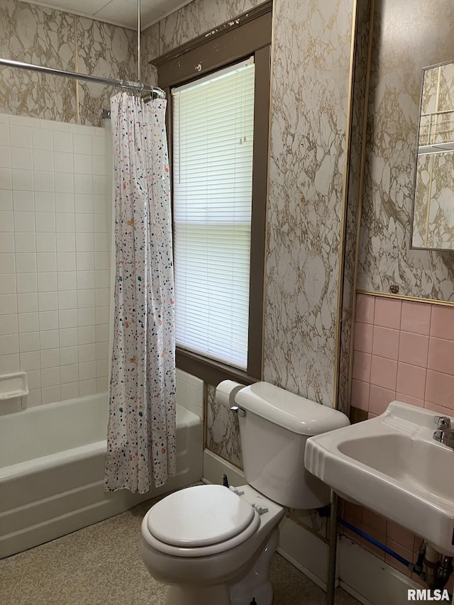 full bathroom featuring toilet, a healthy amount of sunlight, tile walls, and shower / bath combo