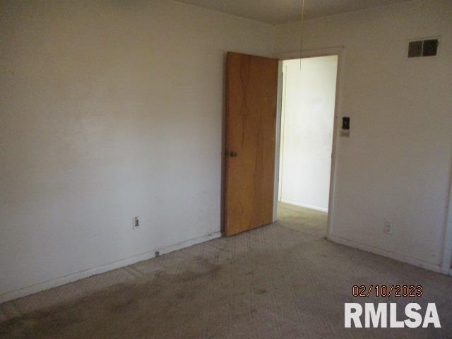 empty room featuring light colored carpet, visible vents, and baseboards