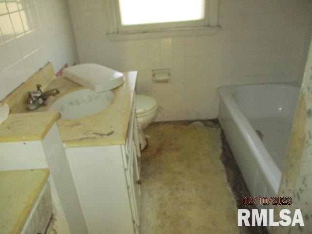 bathroom featuring vanity, tile walls, a bathtub, and toilet