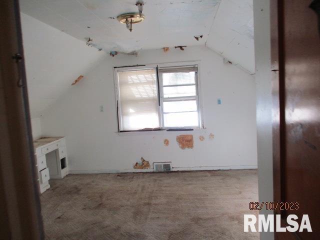 bonus room featuring light carpet, visible vents, and vaulted ceiling