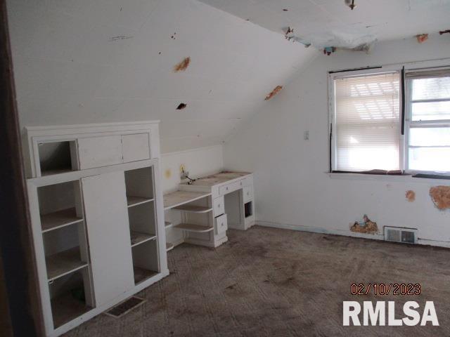 bonus room with lofted ceiling, visible vents, and dark colored carpet