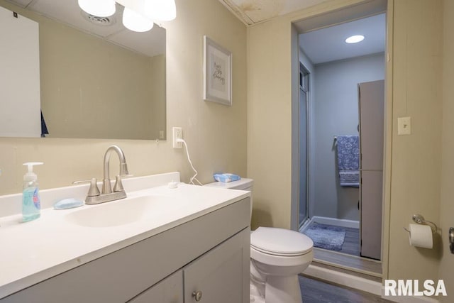 bathroom featuring hardwood / wood-style flooring, vanity, a shower with door, and toilet