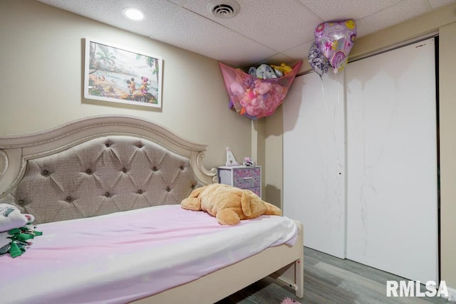 bedroom with wood-type flooring and a paneled ceiling