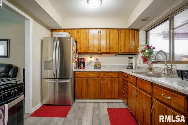 kitchen with sink, range, stainless steel fridge with ice dispenser, and light hardwood / wood-style flooring