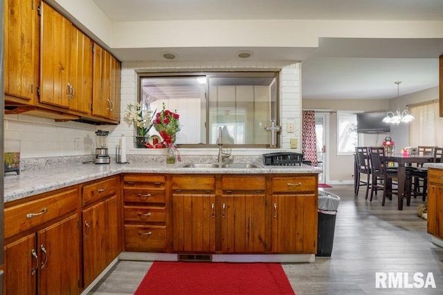 kitchen with a chandelier, hardwood / wood-style flooring, tasteful backsplash, sink, and pendant lighting