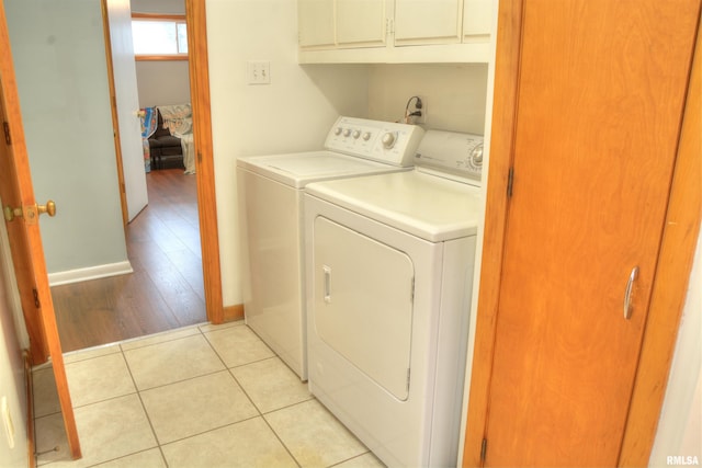 clothes washing area with cabinets, light hardwood / wood-style floors, and washing machine and clothes dryer