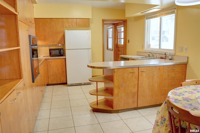 kitchen with sink, white fridge, oven, and light tile patterned floors