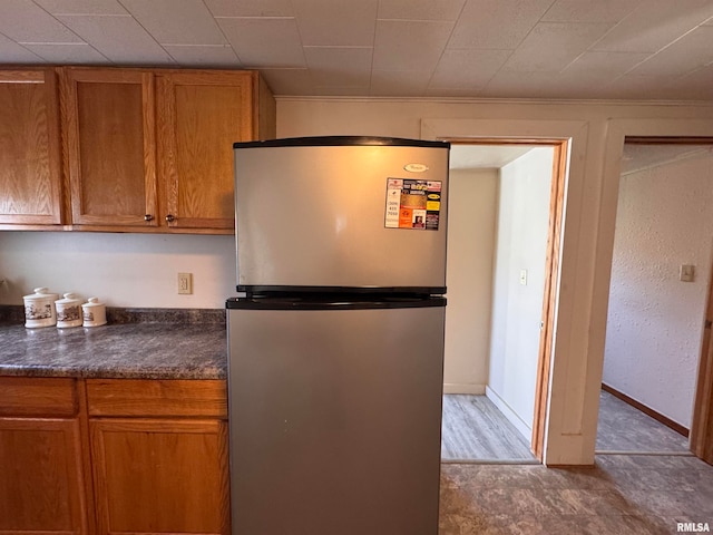 kitchen with stainless steel refrigerator, dark stone countertops, and light wood-type flooring