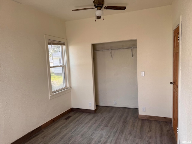 unfurnished bedroom featuring dark hardwood / wood-style flooring, ceiling fan, and a closet