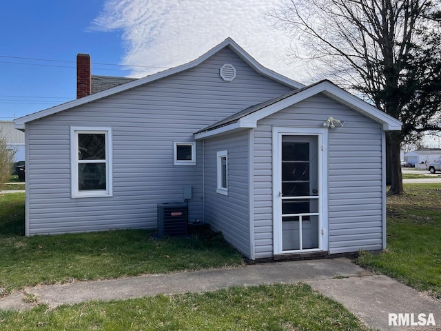 back of property featuring central AC and a lawn