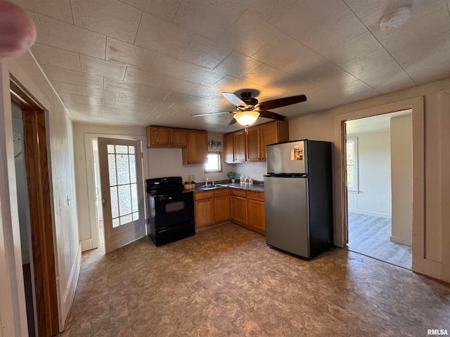 kitchen with ceiling fan, stainless steel fridge, black range with electric stovetop, and sink