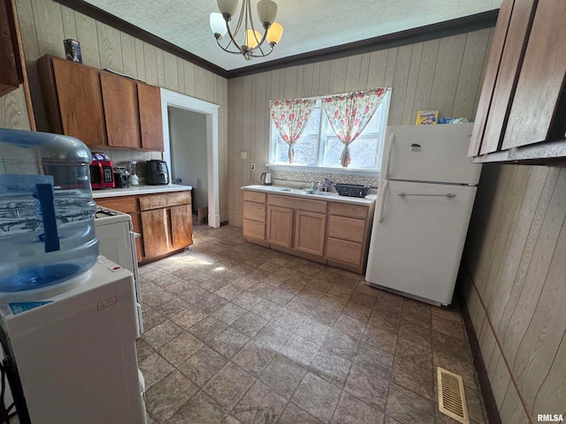 kitchen with crown molding, white fridge, an inviting chandelier, tile floors, and sink