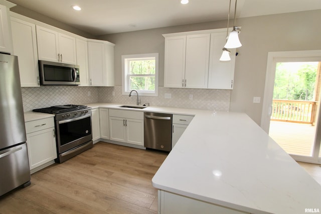 kitchen featuring white cabinetry, sink, stainless steel appliances, decorative light fixtures, and decorative backsplash