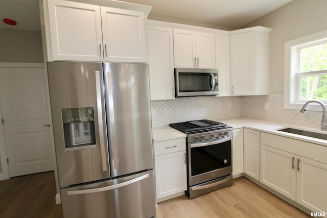 kitchen with white cabinets, backsplash, sink, and stainless steel appliances