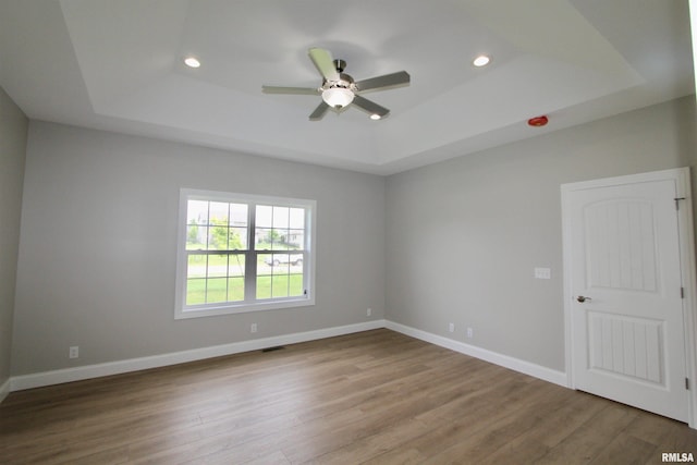 unfurnished room with hardwood / wood-style floors, ceiling fan, and a tray ceiling