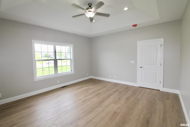 unfurnished room with a tray ceiling, ceiling fan, and light hardwood / wood-style floors