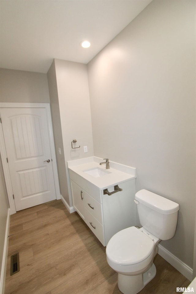 bathroom featuring toilet, vanity, and hardwood / wood-style flooring