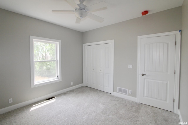 unfurnished bedroom featuring ceiling fan, light colored carpet, and a closet