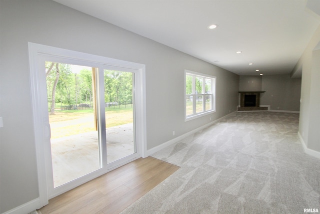 unfurnished living room with light colored carpet and a healthy amount of sunlight