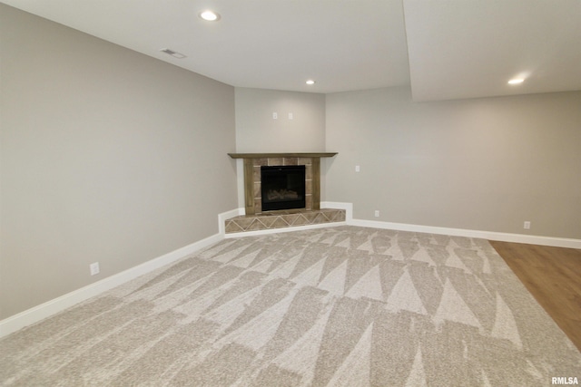 unfurnished living room featuring wood-type flooring and a tiled fireplace