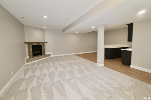 basement with a tiled fireplace and light hardwood / wood-style floors