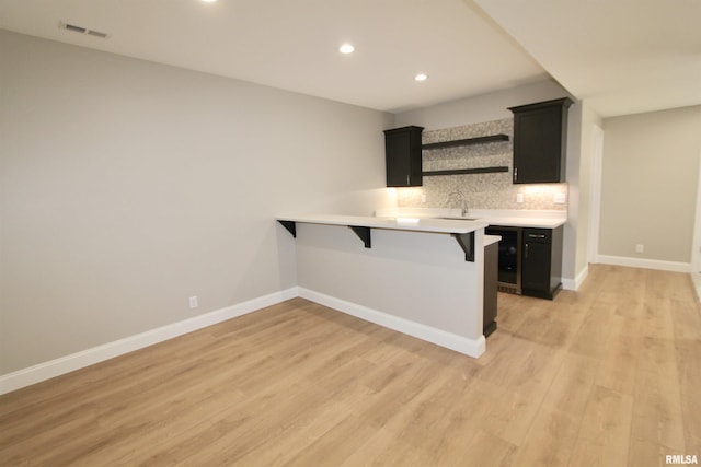 bar featuring backsplash, sink, and light hardwood / wood-style floors