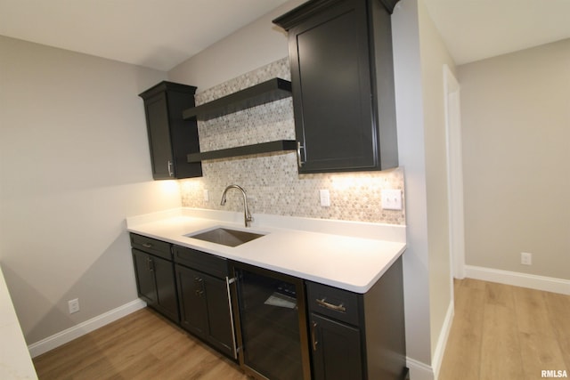 kitchen featuring dishwasher, backsplash, light hardwood / wood-style floors, and sink