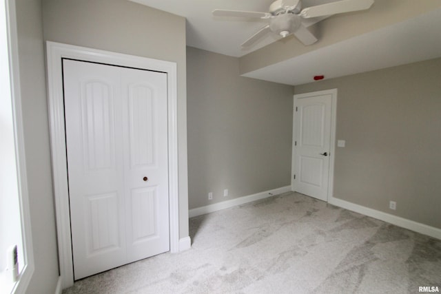 unfurnished bedroom with ceiling fan, light colored carpet, and a closet