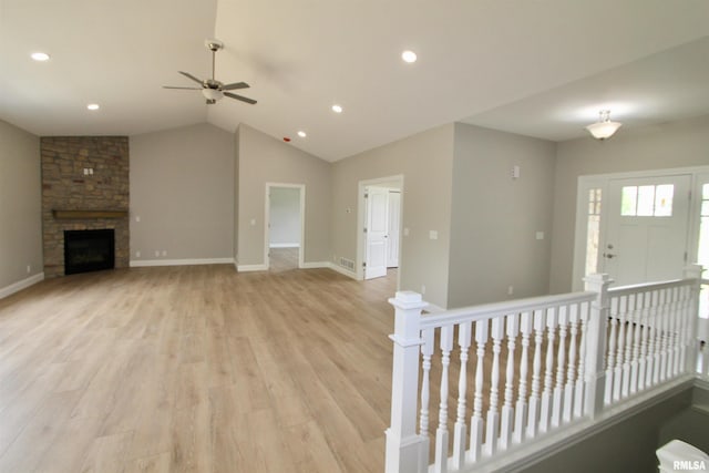 unfurnished living room with a fireplace, light wood-type flooring, ceiling fan, and lofted ceiling