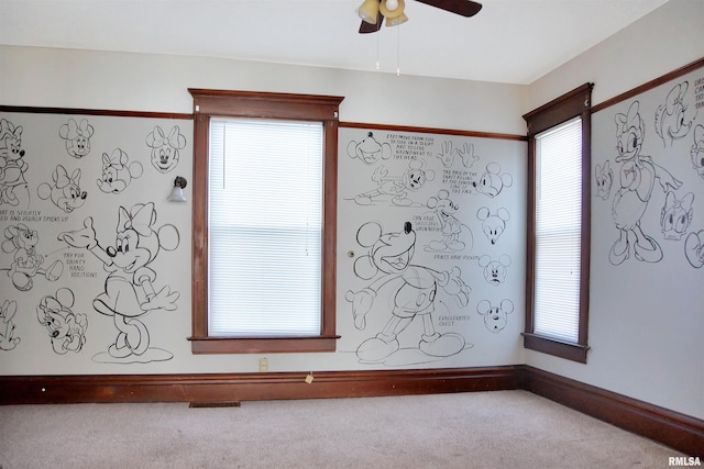 carpeted spare room featuring a healthy amount of sunlight and ceiling fan