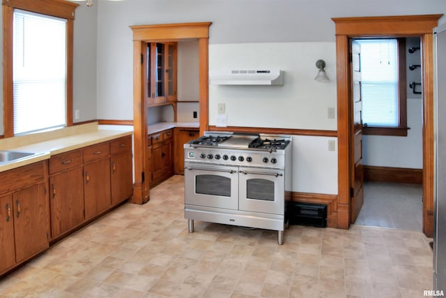 kitchen featuring range with two ovens, plenty of natural light, and light tile flooring