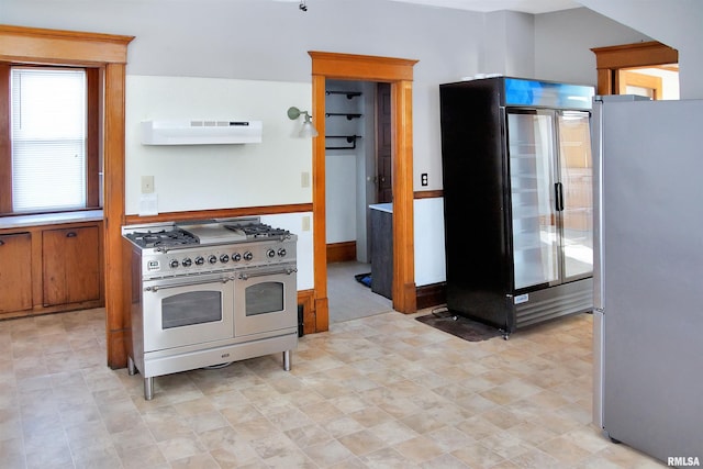 kitchen featuring high quality appliances, light tile floors, and ventilation hood