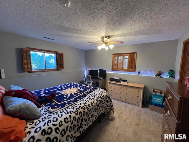 carpeted bedroom with ceiling fan and a textured ceiling