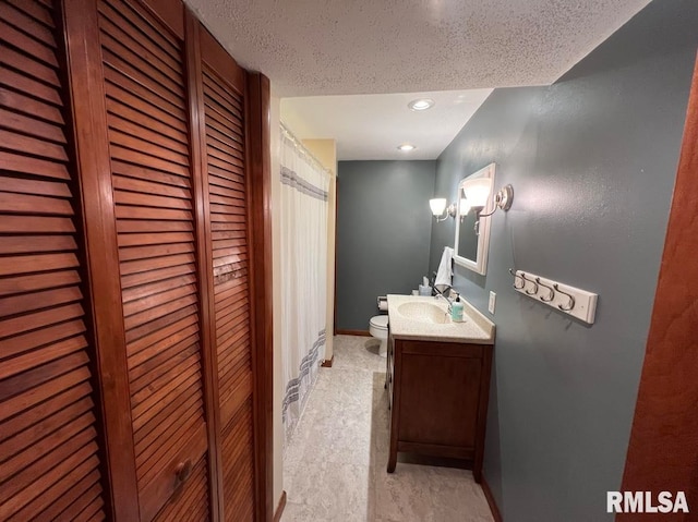 bathroom featuring a textured ceiling, toilet, and vanity