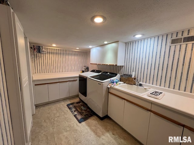 kitchen with sink, a textured ceiling, white cabinetry, and independent washer and dryer