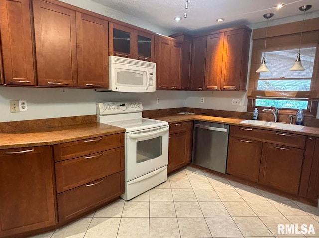 kitchen featuring sink, decorative light fixtures, light tile patterned flooring, and white appliances