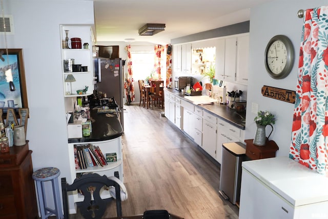 kitchen featuring light hardwood / wood-style flooring, stainless steel refrigerator, and white cabinetry