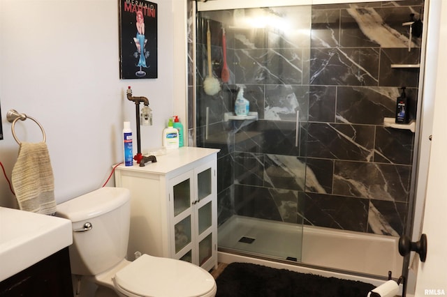 bathroom featuring a shower with door, toilet, and vanity