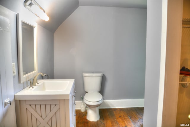 bathroom featuring baseboards, toilet, hardwood / wood-style floors, vaulted ceiling, and vanity