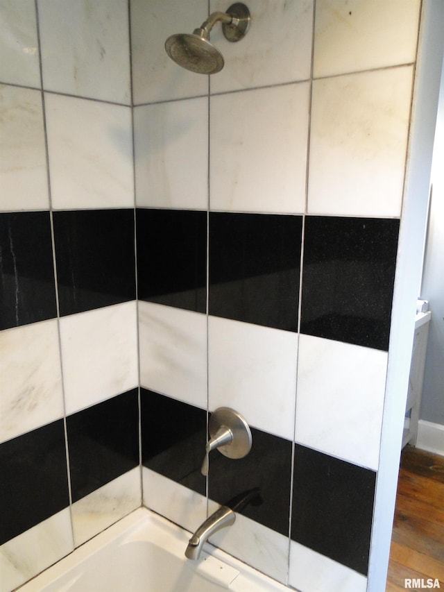 interior details featuring a shower, wood finished floors, and a bathing tub