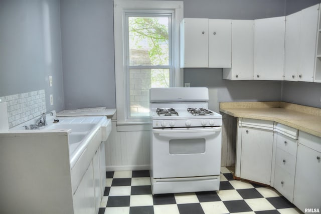 kitchen featuring white gas range oven, white cabinetry, and light tile flooring