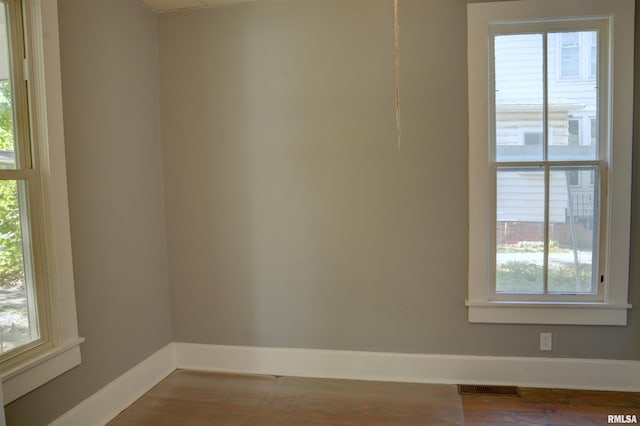 spare room featuring visible vents, baseboards, and wood finished floors