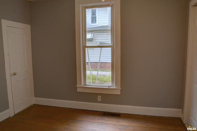 spare room featuring hardwood / wood-style floors, visible vents, and baseboards