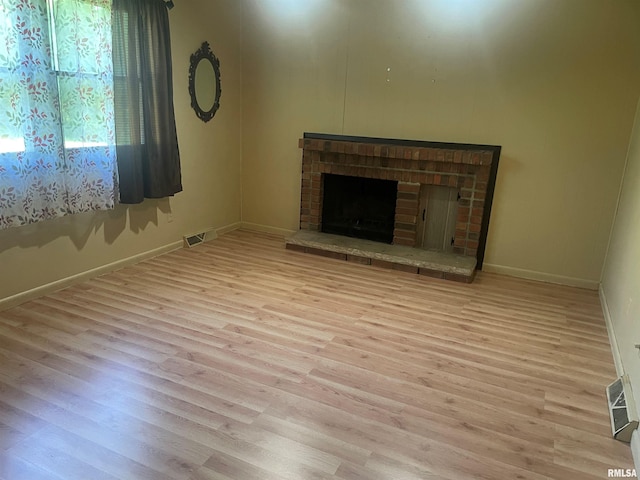 unfurnished living room featuring a brick fireplace and light hardwood / wood-style flooring