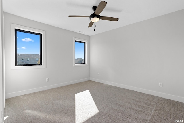 carpeted spare room with ceiling fan and plenty of natural light